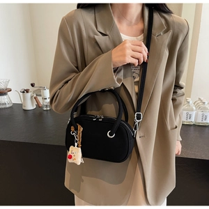 Détail du sac à bandoulière noir avec zips argentés et charmant ours en peluche