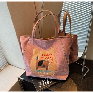 Dettaglio borsa shopper rosa con ricamo a gatto e cerniera decorativa laterale su sfondo