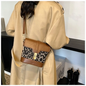 Detail of leopard print bucket bag with golden twist lock and brown leather strap