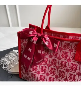 Close-up of red bridal tote bag with Xi character pattern and decorative silk ribbon