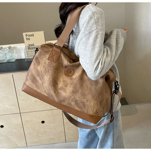 Close-up of vintage brown canvas travel bag with leather accents and adjustable shoulder strap