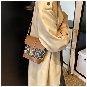 Detail of vintage leopard print crossbody bag with golden twist lock on a khaki coat