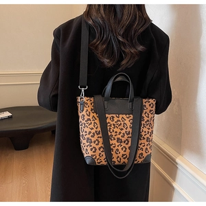 Close-up of leopard print tote bag with black handles and reinforced corners on a model
