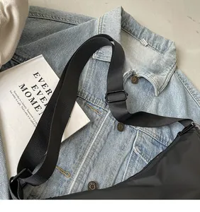 Gros plan du sac bandoulière en nylon noir avec sangle réglable sur veste en jean