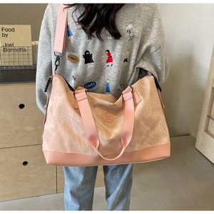 Detail of pink travel bag showing reinforced bottom leather and wide fabric shoulder strap