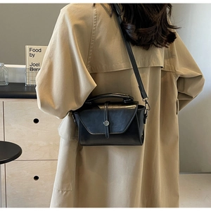 Detail of vintage black crossbody bag with glossy finish and silver metal buckle accent