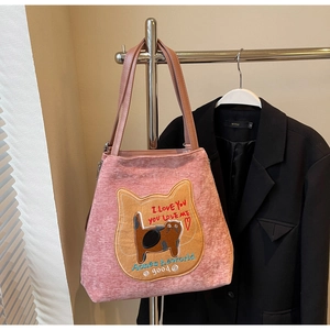 Dettaglio del ricamo a forma di gatto su borsa tote in velluto rosa per pendolari
