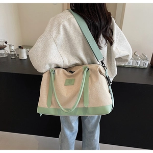 Détail du sac de voyage en toile avec finitions en cuir vert et bandoulière réglable