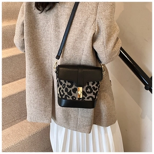 Detail of leopard print bucket bag with gold clasp shown on model in neutral outfit