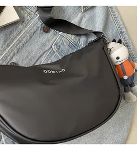 Détail du sac bandoulière noir en demi-lune avec logo blanc et charm peluche âne orange