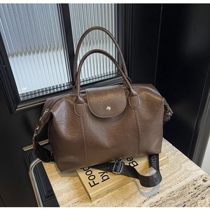 Close-up of brown pebbled leather tote with a wide canvas strap and silver hardware