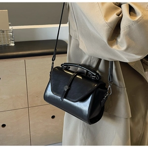 Black leather flap bag on model showing mixed textures and metal ring buckle detail