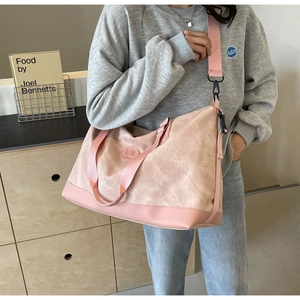 Pink canvas travel bag with wide shoulder strap shown being worn by a model