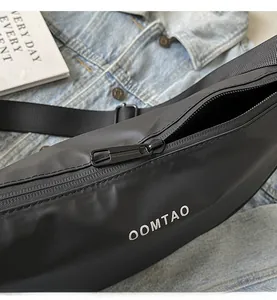 Gros plan sur la fermeture éclair en métal noir et le logo OOMTAO blanc sur le sac en nylon