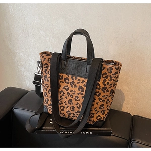 Close-up of leopard print bucket bag with black leather edges and wide shoulder strap