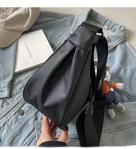 Détail d'un sac bandoulière noir en nylon avec large sangle et texture plissée