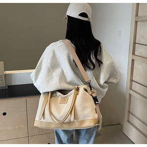 Détail du sac de voyage en toile crème avec finitions en cuir et bandoulière réglable