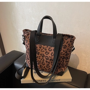 Close-up of leopard print canvas tote with black leather trim and wide fabric strap