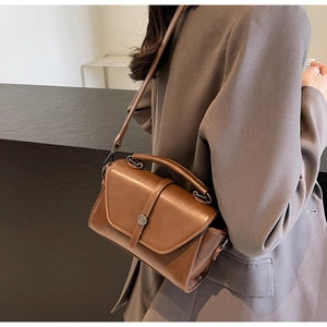 Side view of a vintage dark brown shoulder bag on a model in a grey blazer jacket