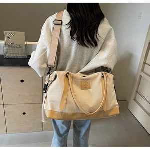 Détail d'un grand sac de voyage en toile avec anses en cuir porté dans un décor intérieur