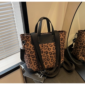 Detail of leopard print tote bag featuring black leather handles and silver hardware