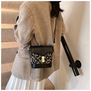 Detail of retro leopard print bucket bag with gold lock and leather stitching on stairs