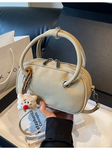 Sac à main beige en daim avec poignées en U, pendentif peluche et bandoulière