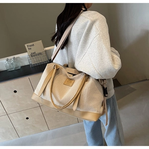 Grand sac fourre-tout en toile beige avec bordure en cuir marron porté par un mannequin