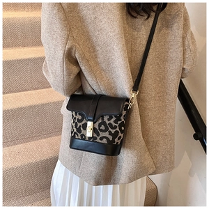 Detail view of leopard print bucket bag with contrast leather and gold metal twist lock