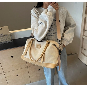 Vue détaillée du grand sac de voyage en toile avec finitions cuir porté en bandoulière