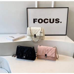 Close-up of V-shaped quilted chain bags in white, black and pink with metal locks