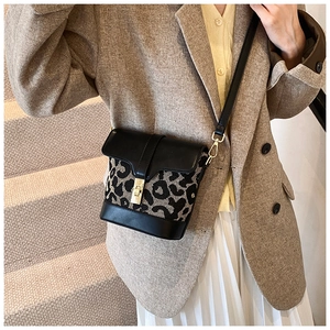 Detail shot of mini leopard print bucket bag with gold hardware on a stylish model