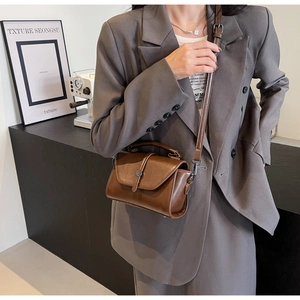 Detail of vintage brown leather crossbody bag with top handle and adjustable shoulder strap
