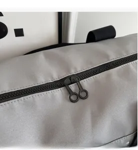 Close-up of smooth dual metal zippers and textured gray fabric on a fitness travel bag