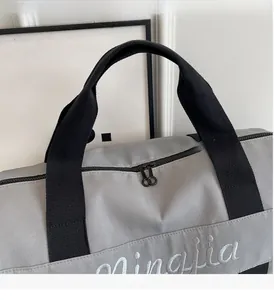 Close-up of grey fitness bag with reinforced black handles and mingjia embroidery