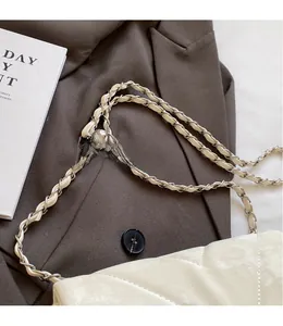 Close-up of beige quilted crossbody bag with adjustable silver ball chain on a blazer