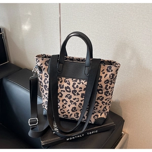 Close-up of leopard print tote bag featuring black leather trim and wide fabric strap