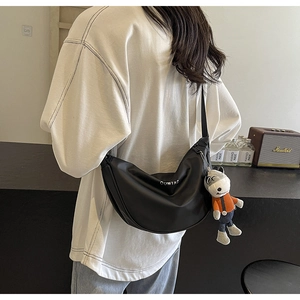 Détail d'un sac demi-lune noir avec logo blanc et breloque en peluche d'âne mignon