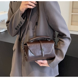 Close-up of vintage brown leather handbag with metallic clasp and round top handle