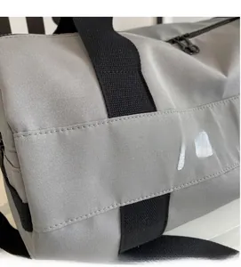 Detail view of grey gym bag with durable nylon texture, black handles and Mine embroidery
