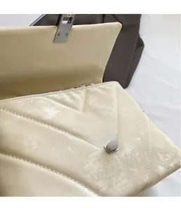 Macro detail of silver turn-lock and quilted V-pattern on beige crossbody bag
