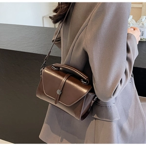 Detail view of dark brown vintage crossbody bag with flap cover and metallic round buckle