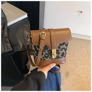Close-up of vintage brown leather cross-body bag with leopard pattern and gold twist lock