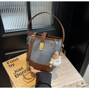 Detail van denim emmertas met gouden draaisluiting en schattige pluche hanger