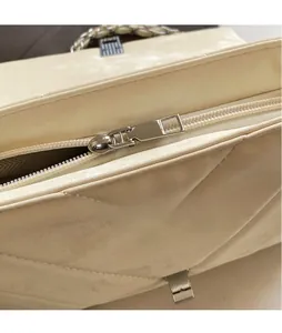 Detail shot of silver metal zipper puller on cream white quilted leather shoulder bag