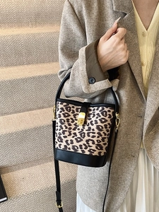 Retro leopard print bucket bag with gold lock and black handle shown in a street style view
