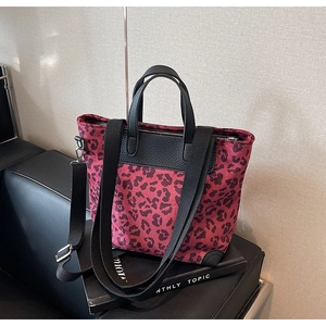 Detail of red leopard print tote with black pebbled leather trim and detachable strap