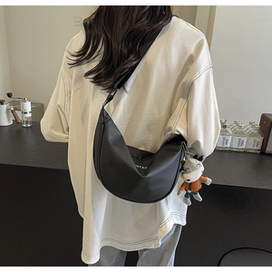 Détail du sac bandoulière demi-lune noir mat avec sangle réglable et peluche loup mignonne