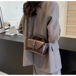 Detailed view of dark brown retro square handbag with metallic buckle and leather strap