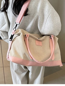 Grand sac de voyage en toile beige et cuir rose, porté à l'épaule, vue latérale chic